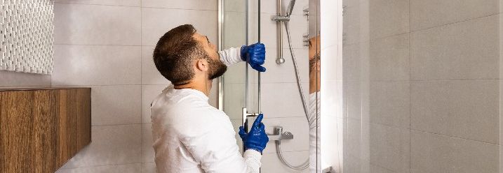 Mann montiert Duschabtrennung
